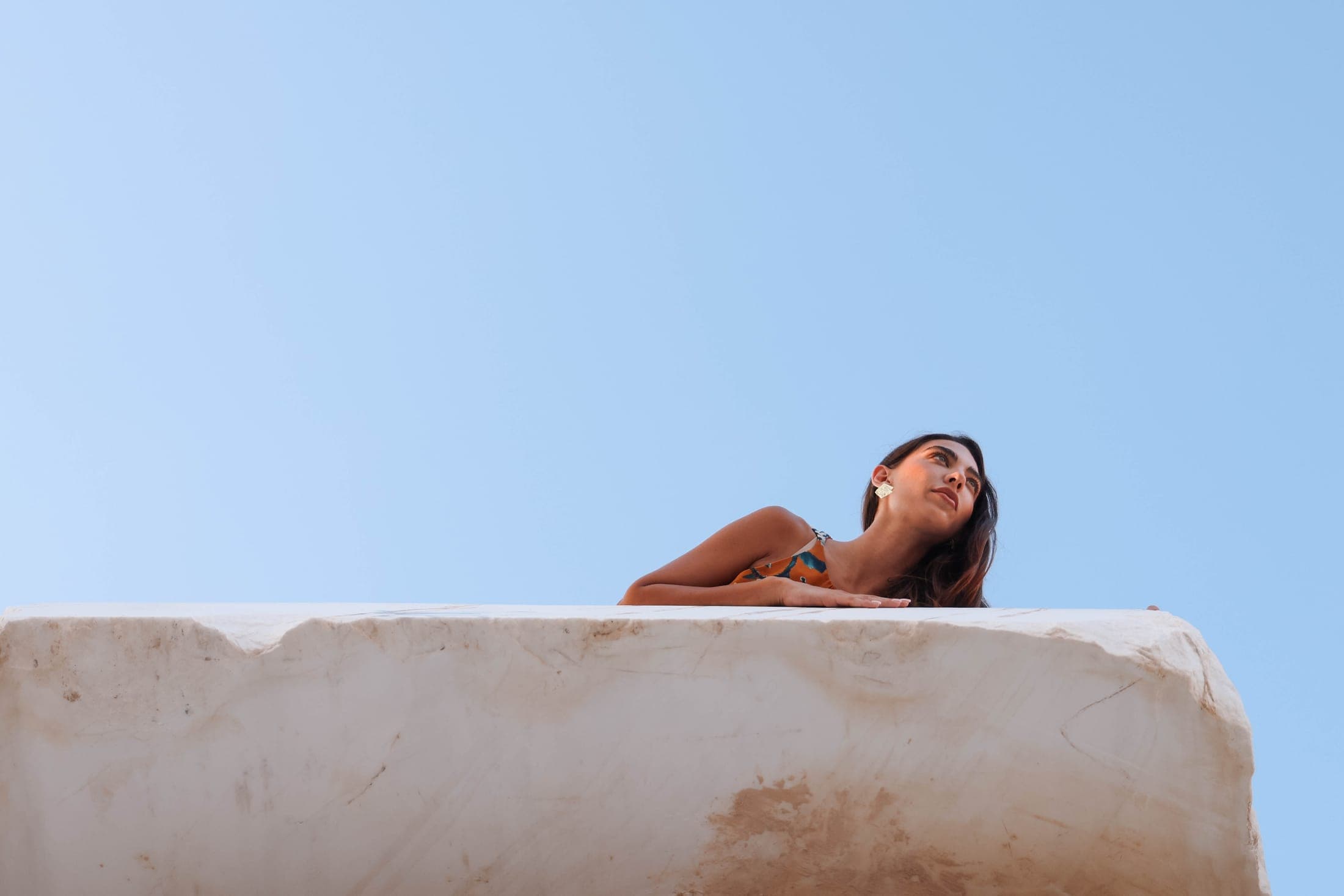 A figure resting on a white marble block under a clear Beirut sky at the Zein Group yard