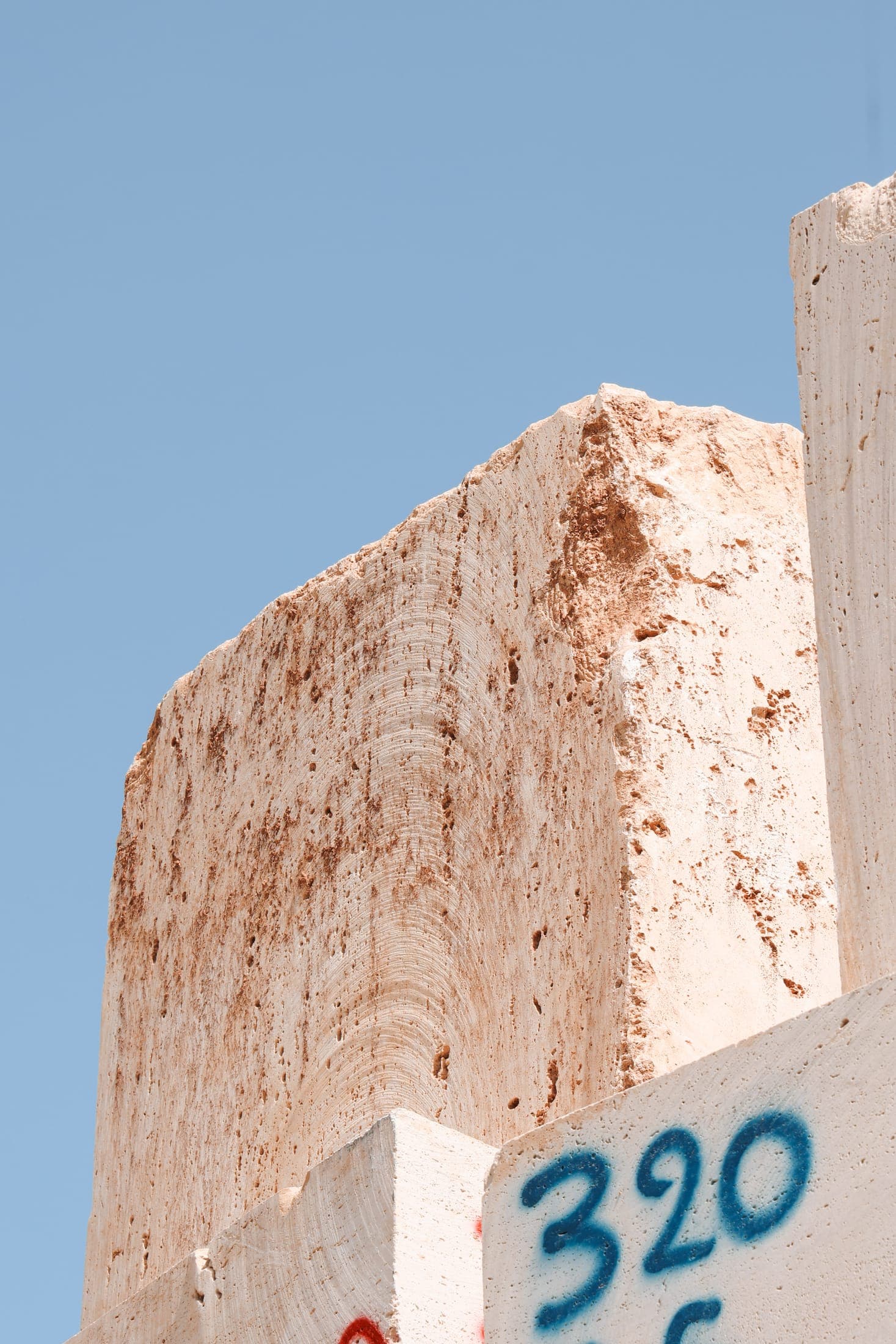 A white marble block marked 320 against a clear blue sky