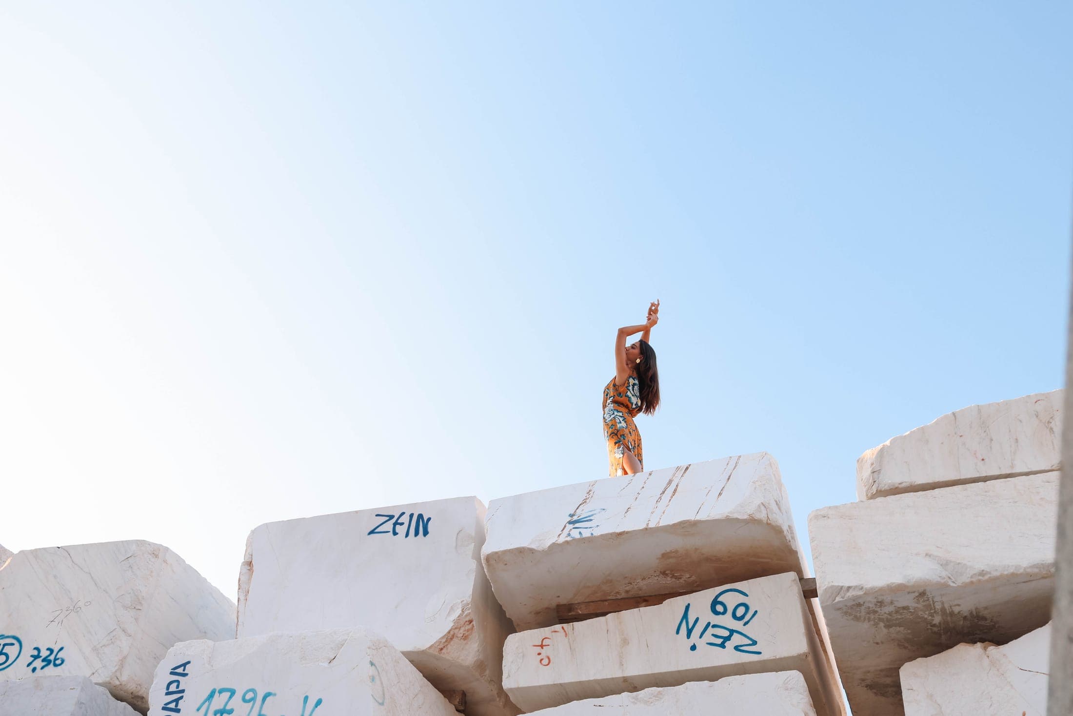 A small figure on top of the marble blocks under a wide blue sky