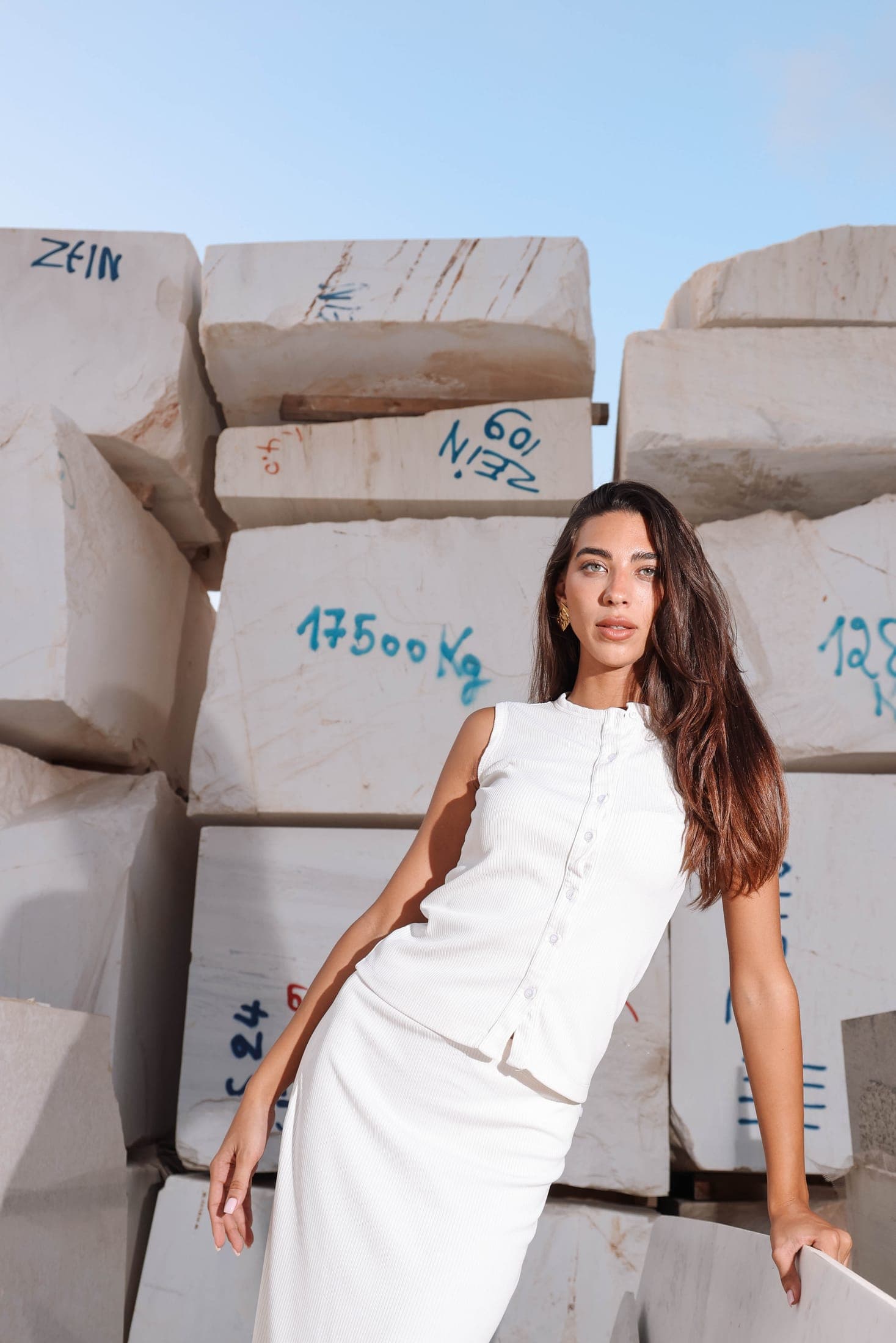 A figure in white standing among white marble blocks marked ZEIN at the Zein Group yard