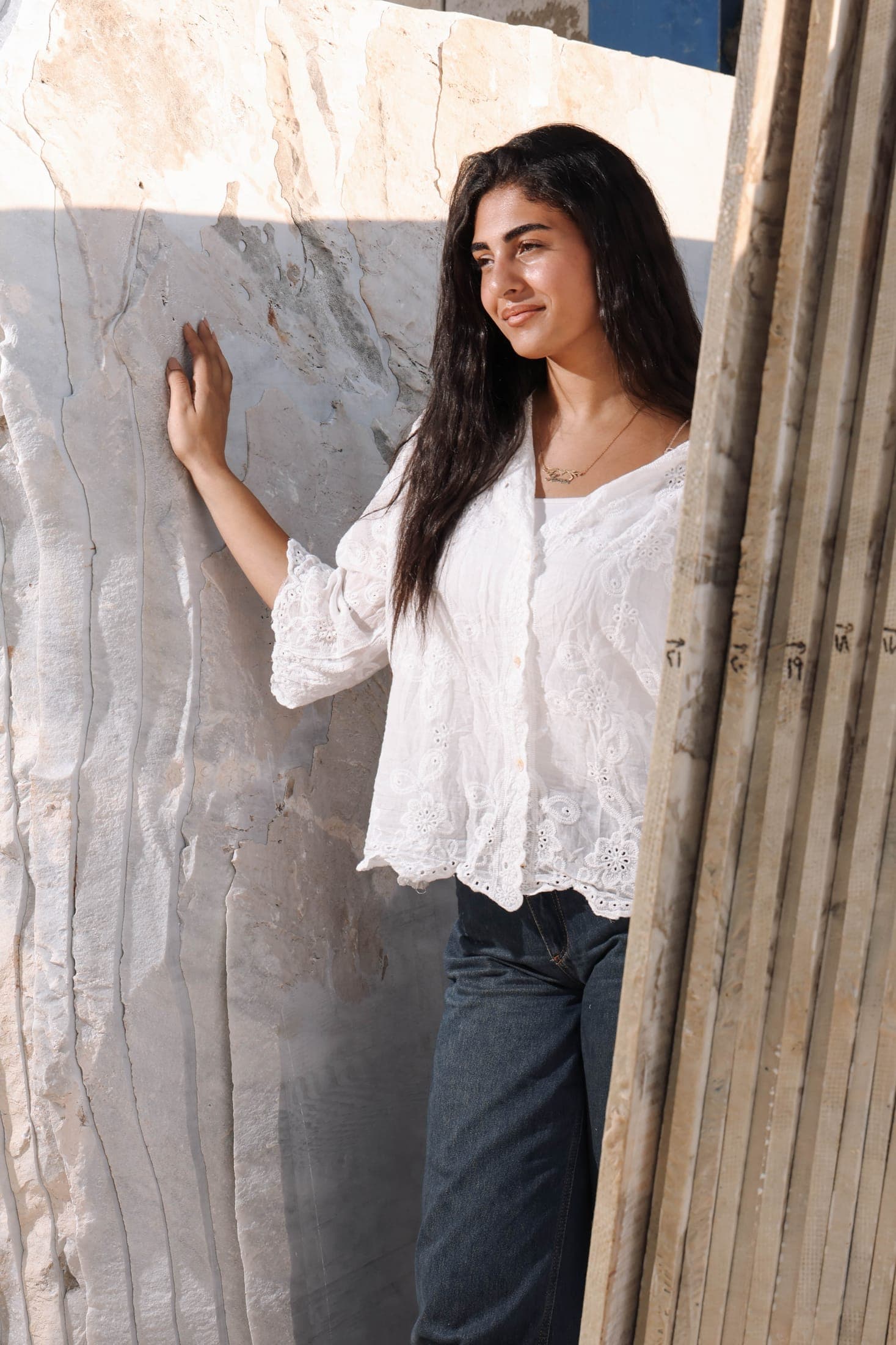 A figure in white lace leaning on a grey-veined marble slab at the rack
