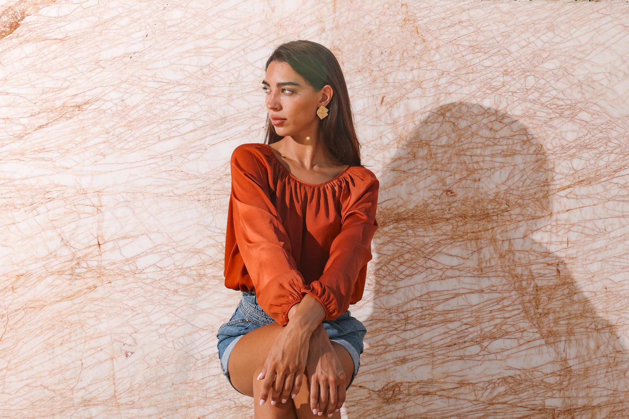 A figure in a rust blouse seated against a wide gold-veined white marble slab at the Zein Group yard