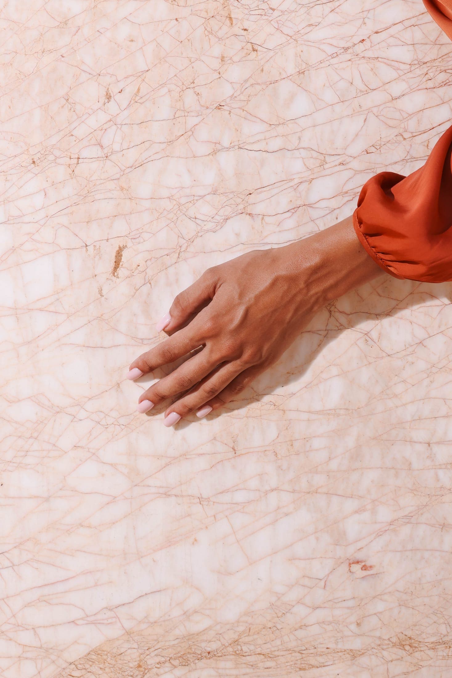 A hand pressed flat against gold-veined white marble