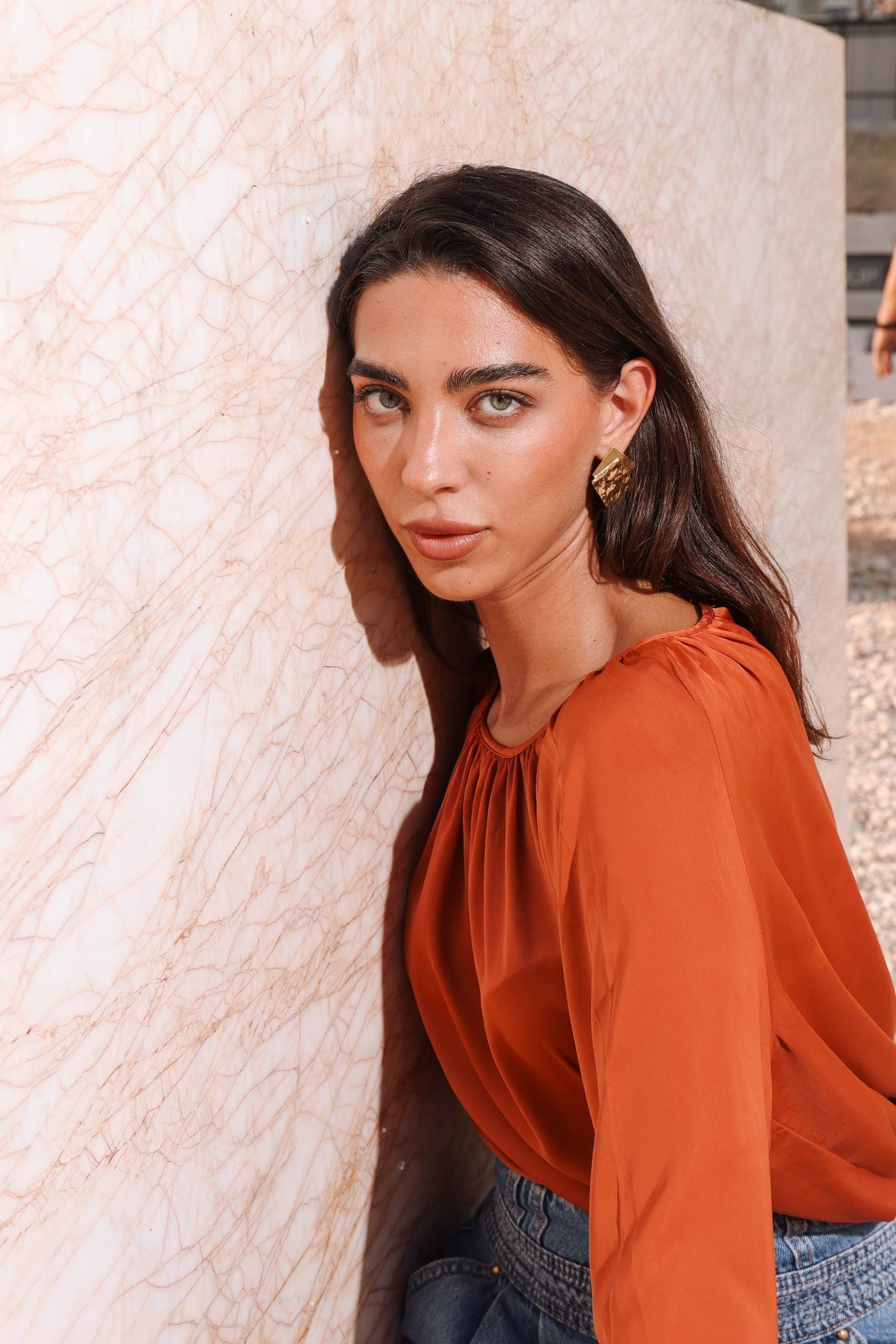 Portrait in a rust blouse against gold-veined white marble