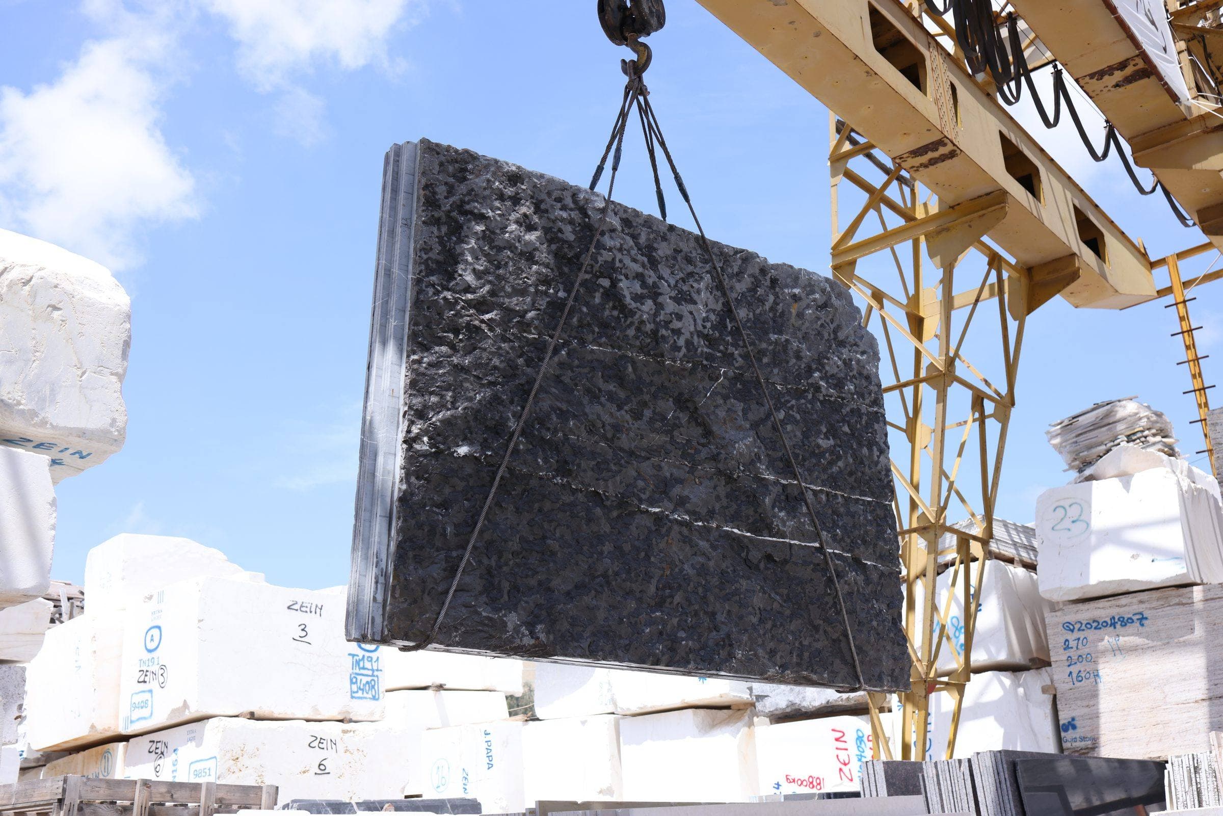 A black marble slab lifted by the overhead crane at the Zein Group stone yard, Beirut
