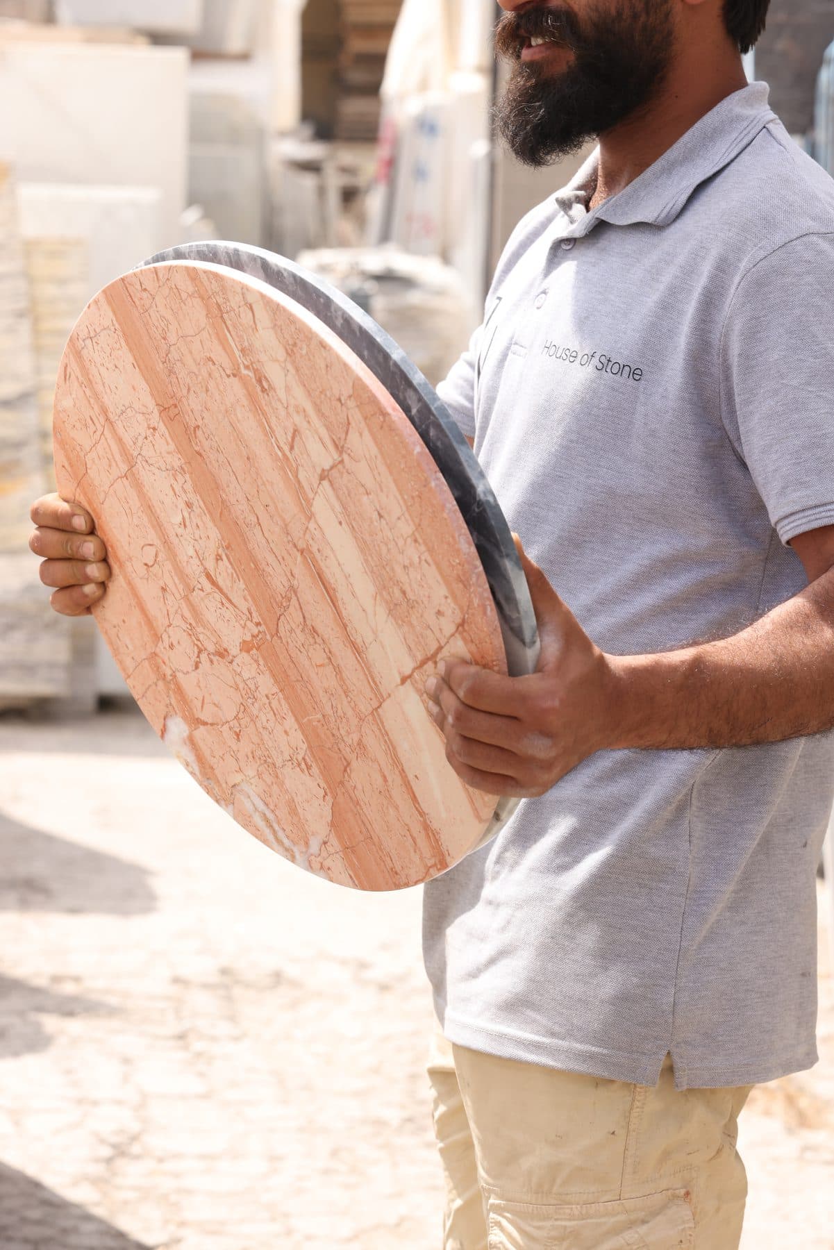 Craftsman carrying a round travertine tabletop at the Zein Group workshop in Beirut