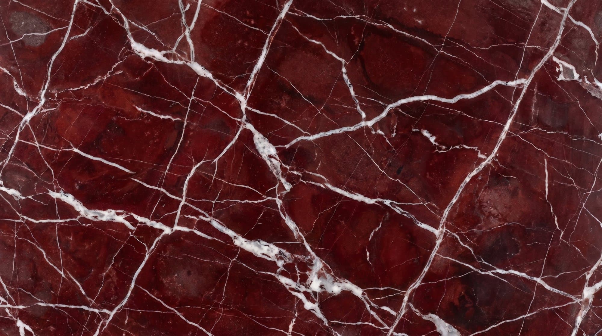 Macro detail of a deep red marble slab with fine white spider veining