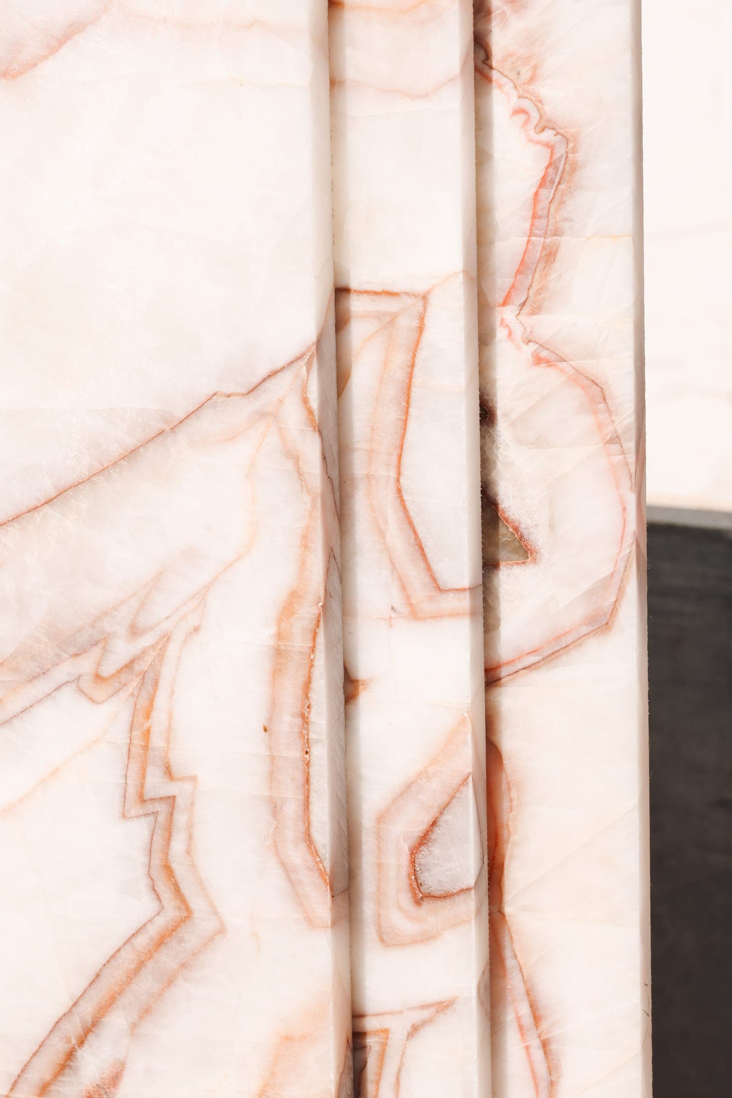 Close-up of a pale stone slab with bold rose and rust veining at the Zein Group stone yard