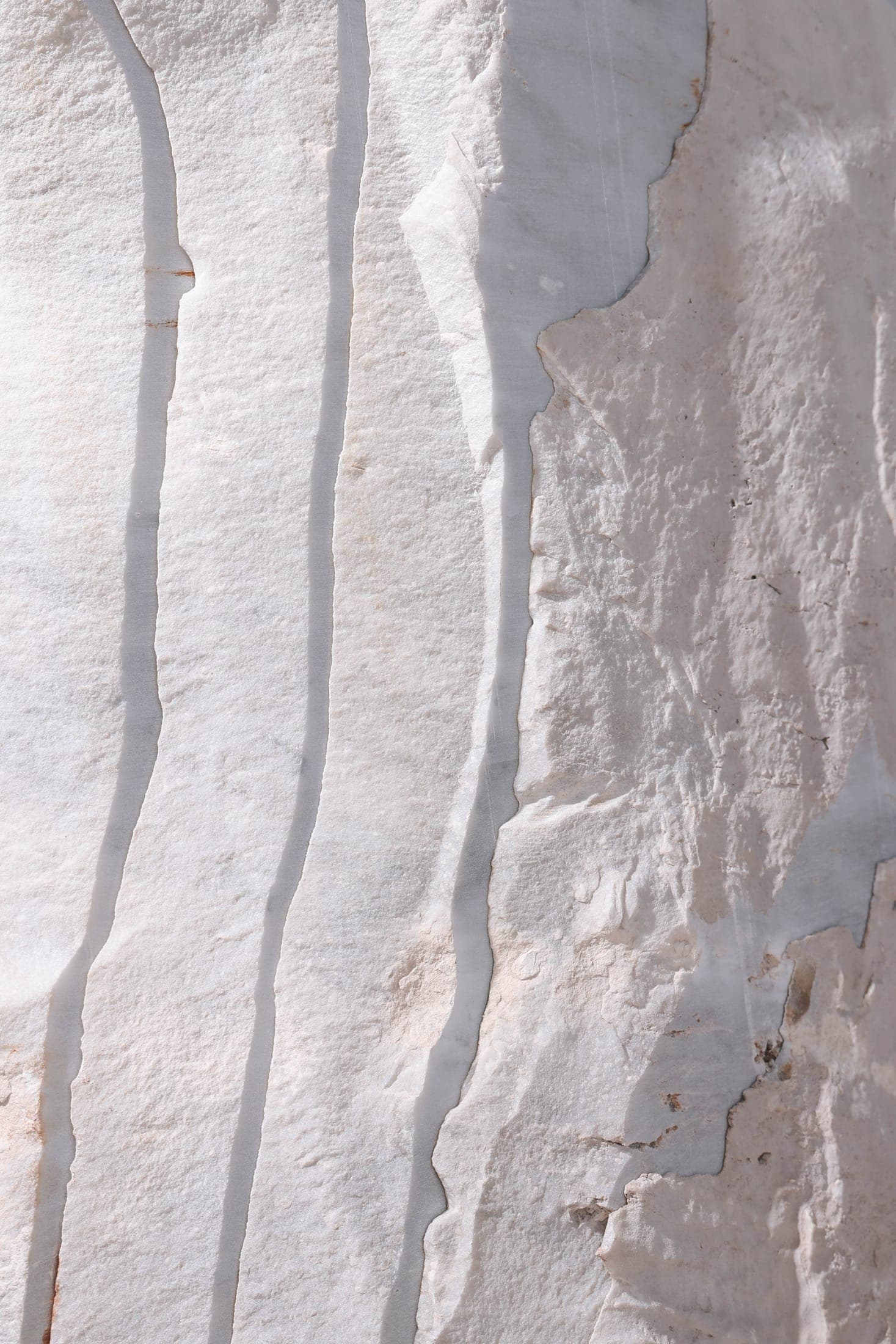 The rough split face of a white stone block in hard sunlight at the Zein Group yard
