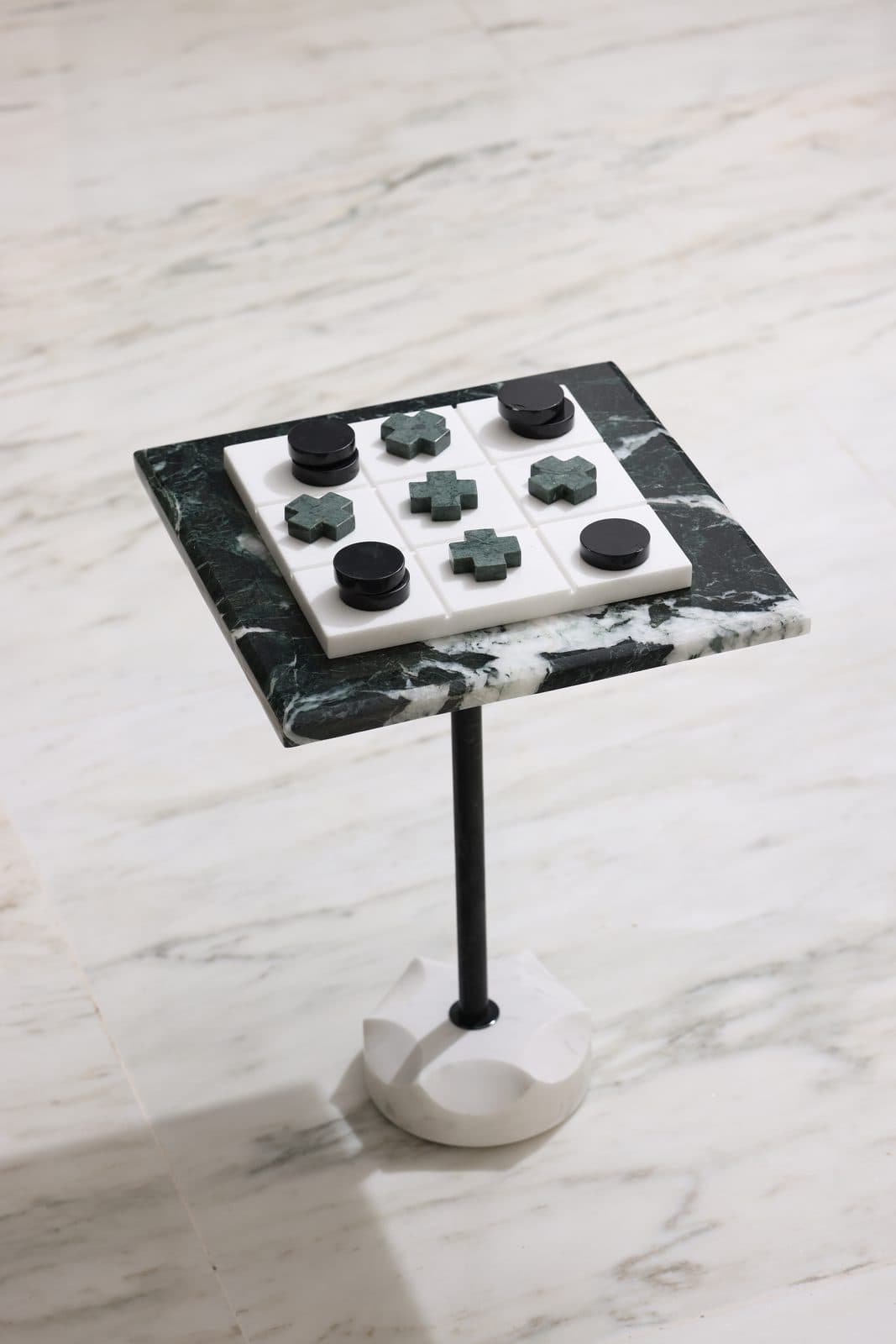 Green marble game table with black stone pieces on white marble