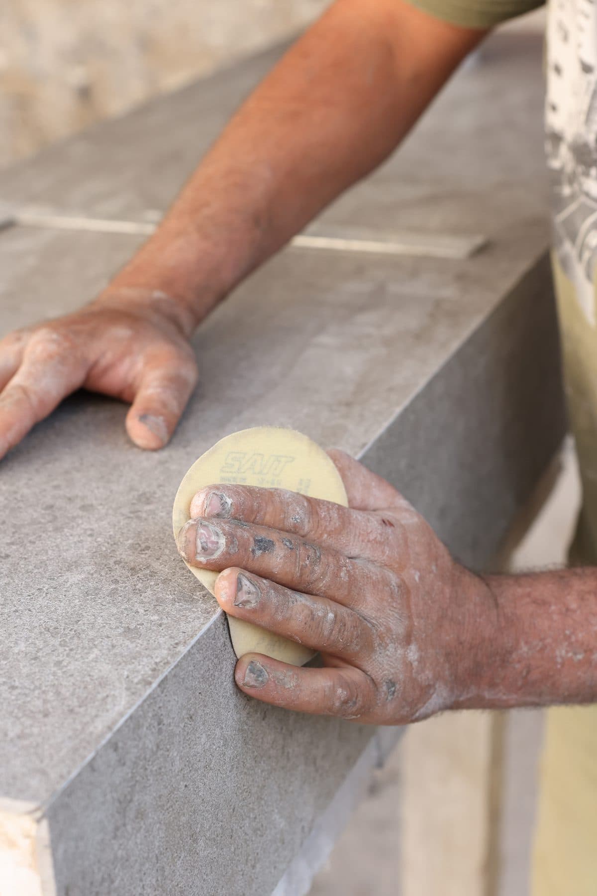 Craftsman's hands finishing and polishing a marble edge at the Zein Group workshop