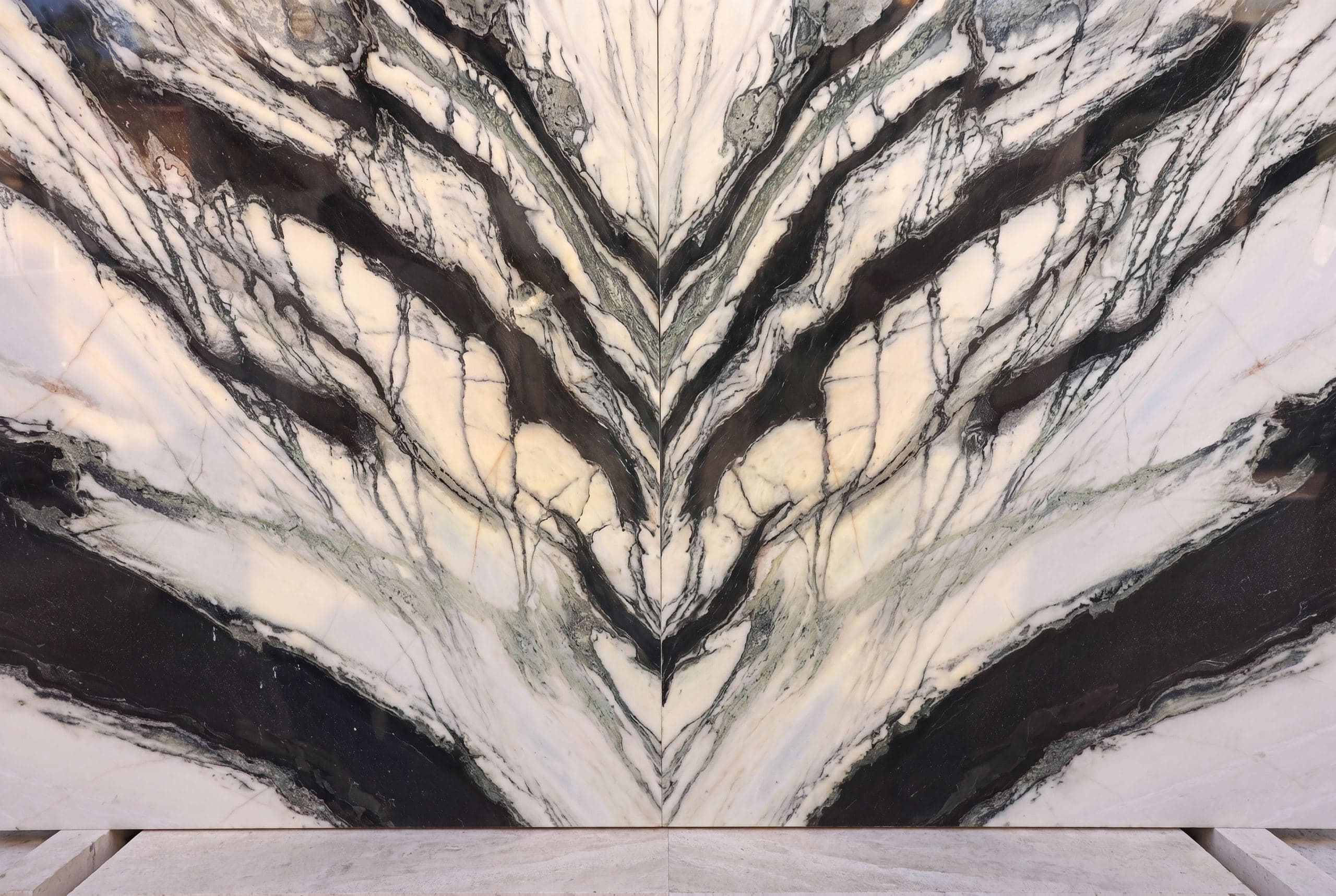A dramatic book-matched marble slab at Zein Group — mirror-cut so its dark veins open symmetrically like wings