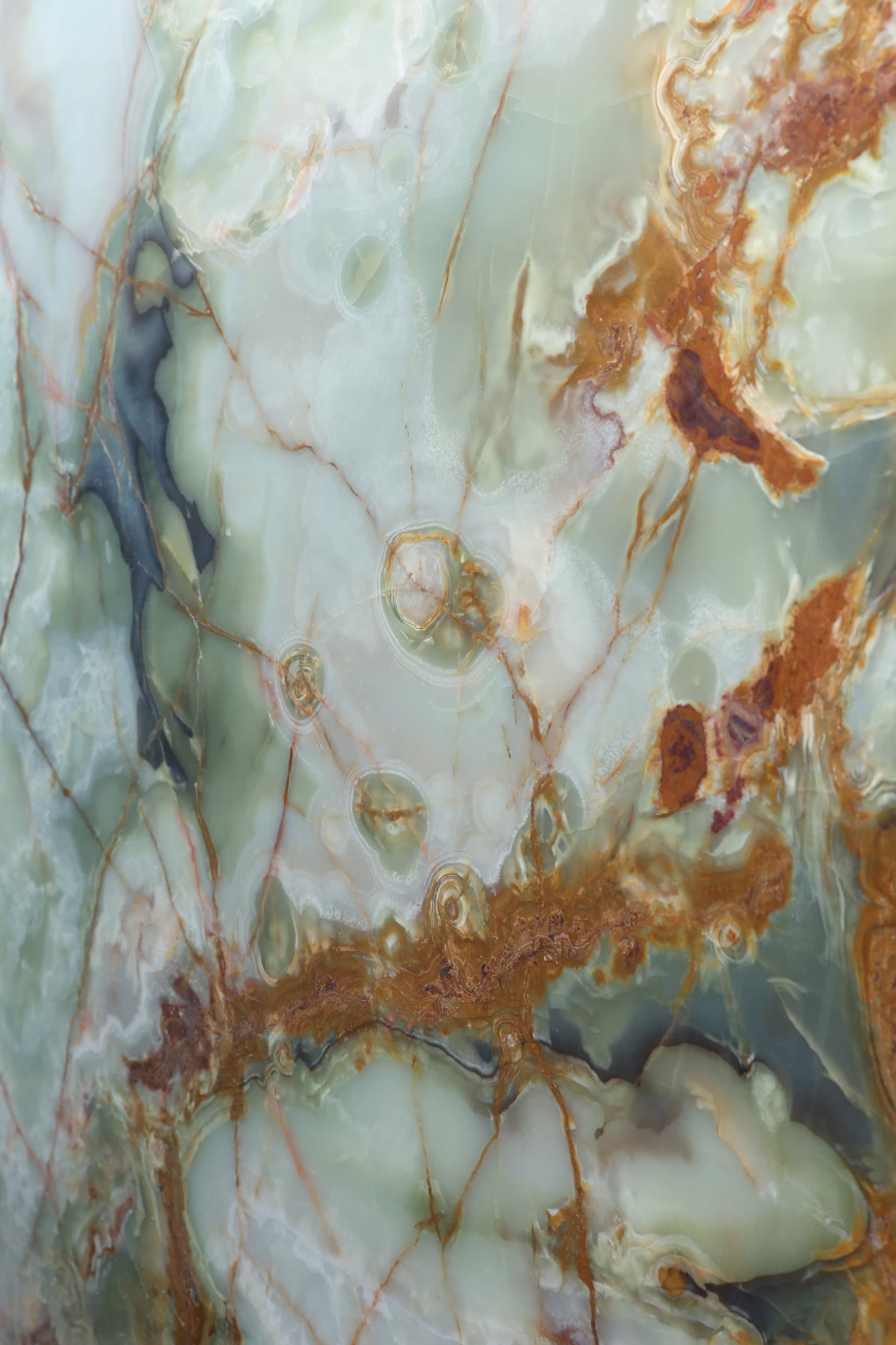 Backlit green onyx threaded with rust and gold veining — Zein Group