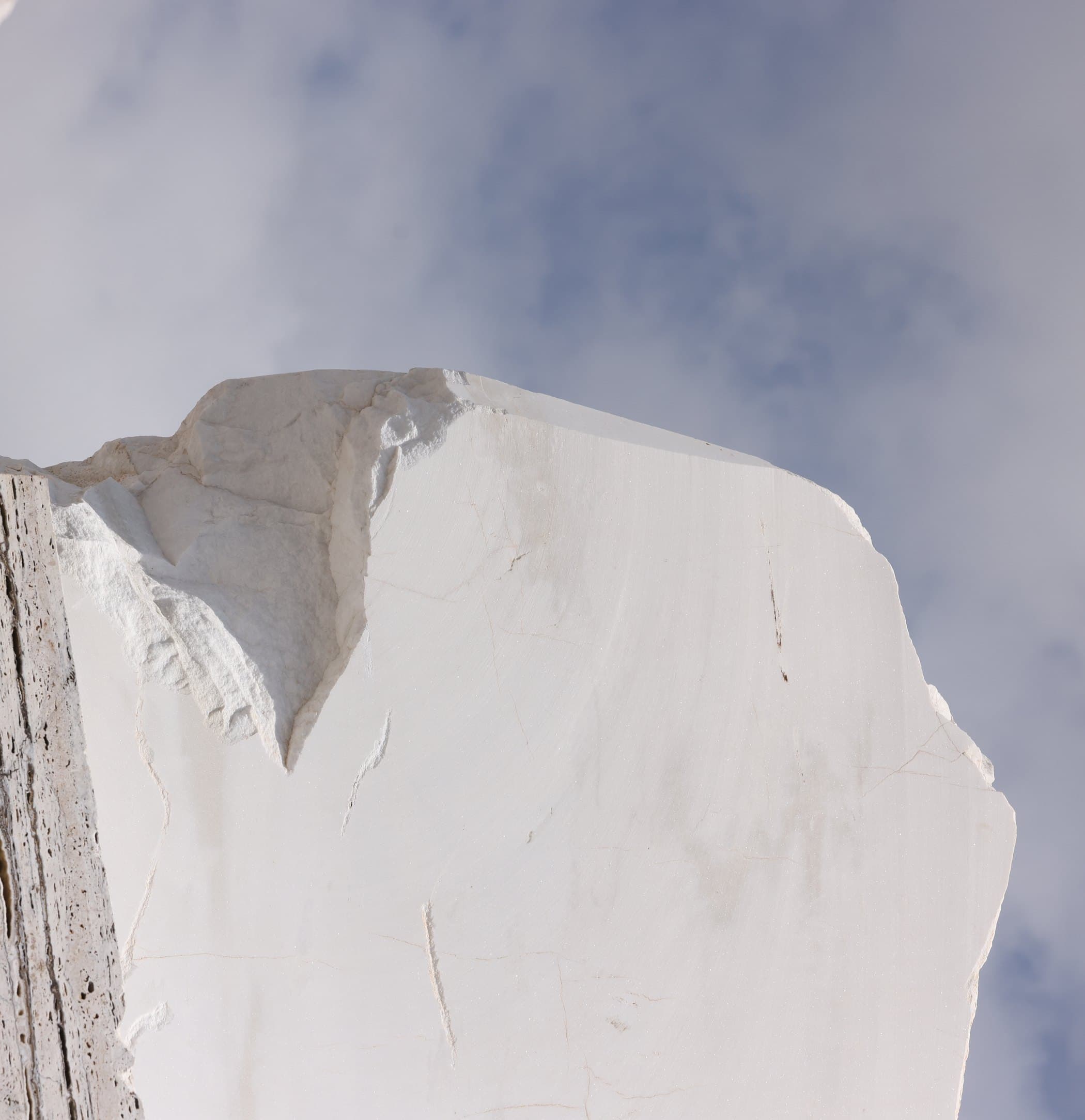 A freshly quarried block of white marble standing against the sky, before cutting