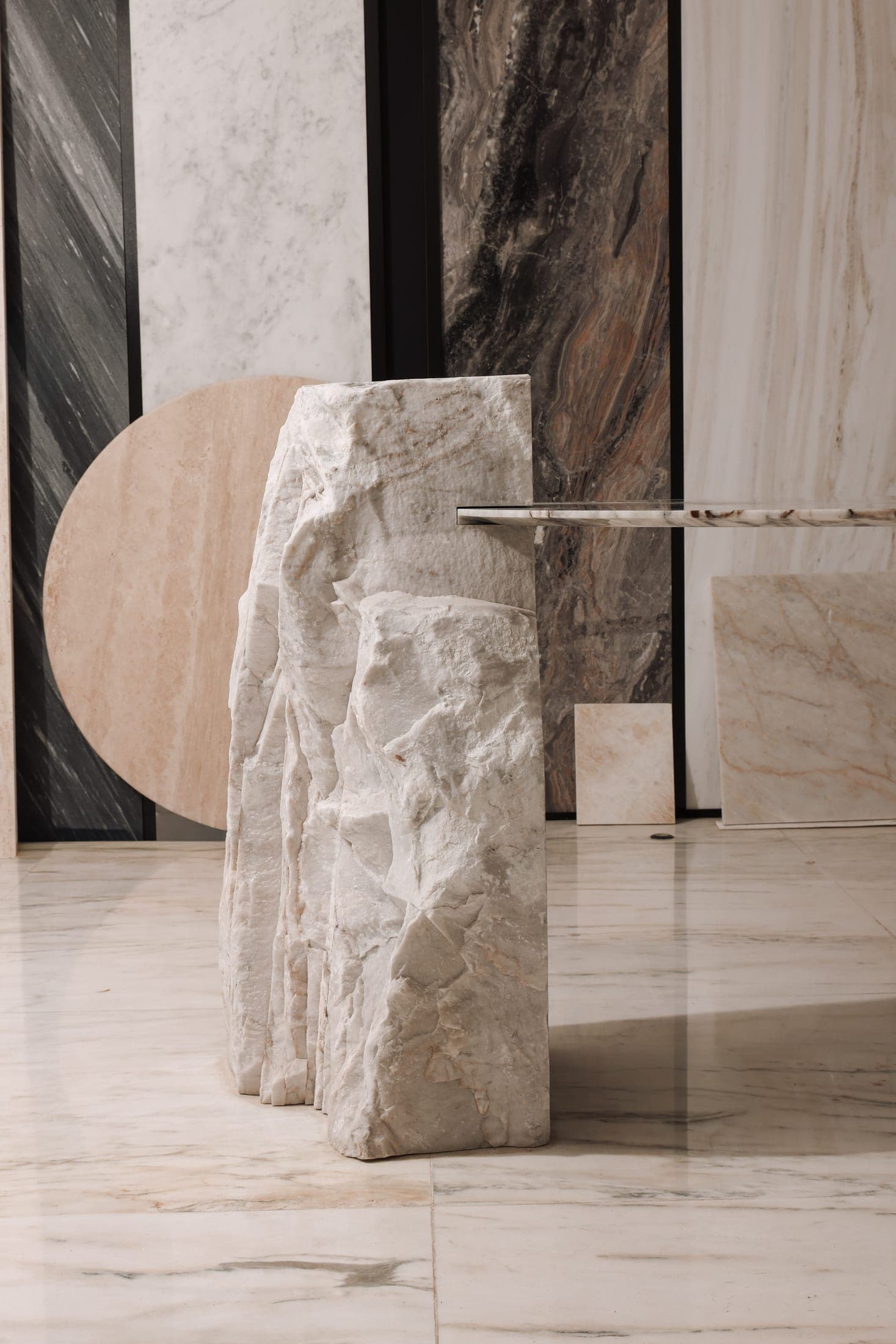 A bespoke Zein Group console — a raw split block carrying a polished veined marble top — standing in place among marble panels