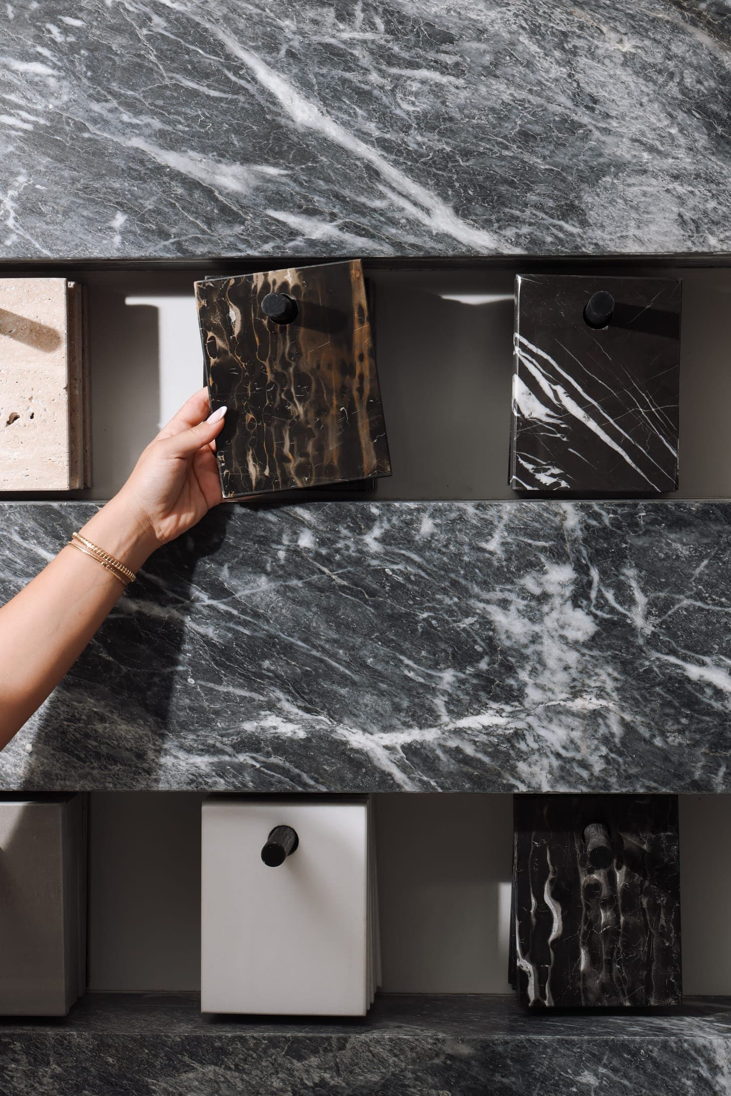 Choosing a black marble sample from the Zein Group sample wall