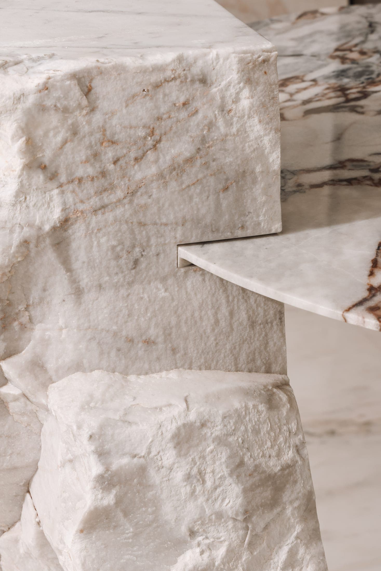 A split-face stone block meeting a polished veined slab top — raw and finished stone in one piece